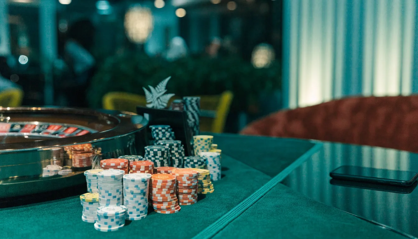 Elegant casino table with chips, roulette wheel, and a face-down smartphone in a luxurious lounge setting