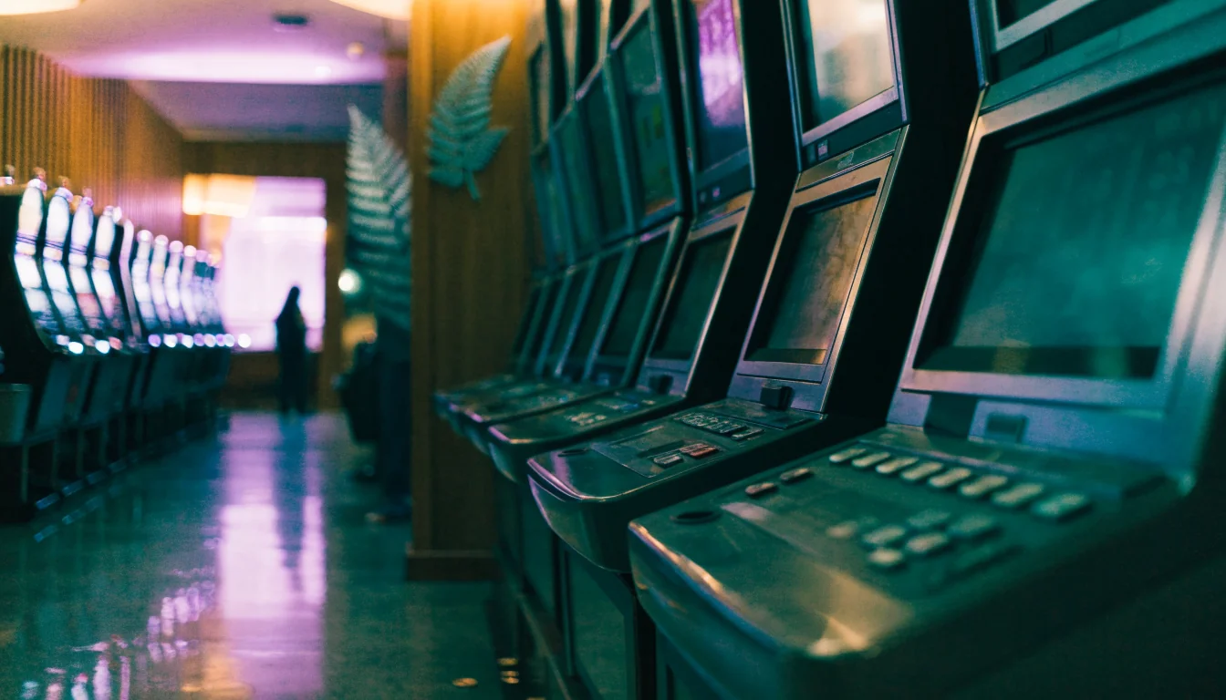 Slot machines in a New Zealand casino with neon lighting and silver fern decor